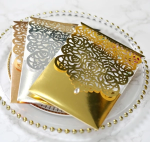 Detail of laser-cut rose patterns on gold and silver metallic wedding invitations