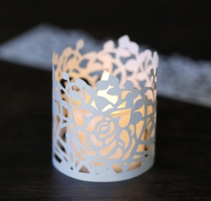 Macro view of white laser-cut rose hollow paper lamp shade with warm LED candle light