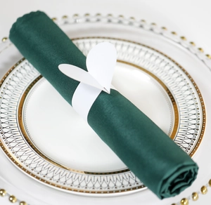 Gros plan d'un rond de serviette papillon en papier blanc sur serviette en tissu vert foncé
