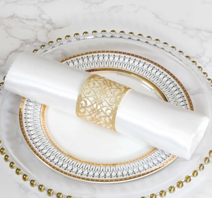 Close-up of golden hollowed-out floral napkin ring on elegant white marble table