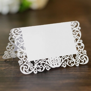 Vue détaillée des cartes de table blanches découpées au laser avec motifs baroques élégants
