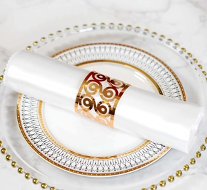 Detail of laser-cut gold napkin rings with geometric scroll patterns on white plates