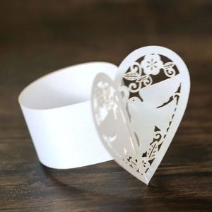 Détail d'un rond de serviette blanc en papier découpé au laser avec motifs de cœur et d'oiseau