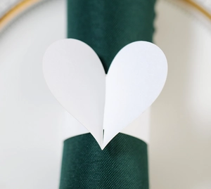 Vue rapprochée d'un élégant rond de serviette cœur blanc sur une serviette en tissu vert foncé