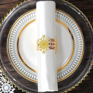 Macro shot of gold snowflake napkin ring on white silk cloth with elegant gold-rimmed plate