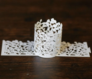 Macro detail of laser-cut paper lampshade featuring intricate rose and leaf patterns