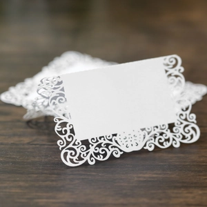 Détail macro du motif en dentelle découpé au laser sur les marque-places blancs de mariage