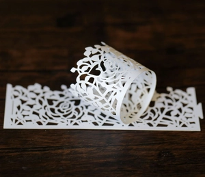 Detail of white laser-cut rose paper sleeve for LED candles and cake decorations