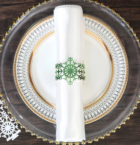 Close-up of green snowflake napkin ring on white napkin with holiday table setting