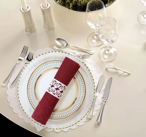 Detail of white geometric cutout napkin ring with deep red fabric linen on dinner plate