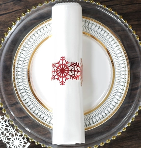 Detailed close-up of a red snowflake napkin ring on a white napkin over a glass plate