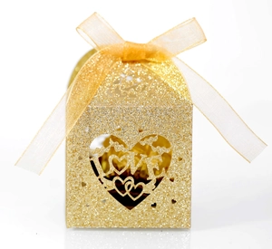 Close-up of gold glitter candy box with hollowed heart-shaped LOVE design and satin ribbon