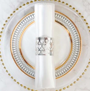 Close-up of silver heart hollow napkin ring with white satin cloth on marble table