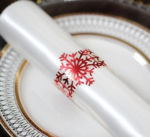Close-up of red laser-cut snowflake napkin ring on white ceramic plate for Christmas decor