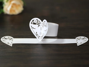 Détail d'un rond de serviette en papier blanc découpé au laser avec motif de cœur