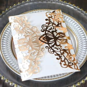 Close-up of laser-cut floral wedding invitation cover with gold foil on wood base