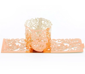 Close-up of rose gold laser-cut paper candle wraps with intricate butterfly vine patterns