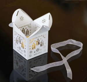 Boîte cadeau de Noël blanche découpée au laser avec motifs de flocon et sapin sur noir