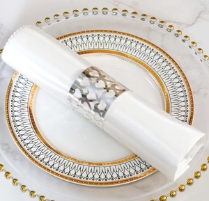 Detail of silver hollow heart napkin ring on white satin fabric and marble background
