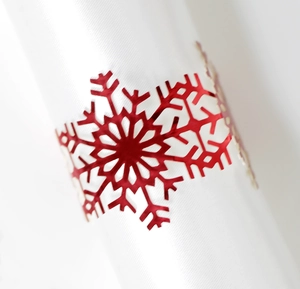 Detailed close-up of a red metal snowflake napkin ring on a white napkin for Christmas decor
