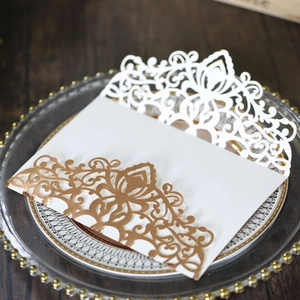 Close-up of laser-cut rose gold and white wedding invitations with floral crown patterns
