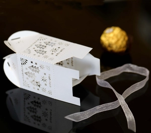 Détail de boîte de bonbons de Noël découpée au laser avec flocons et ruban de soie