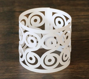 Close-up of laser-cut white butterfly paper napkin ring with intricate spiral patterns