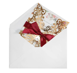 Detail of laser cut wedding invitation with rose gold hollow pattern and burgundy ribbon