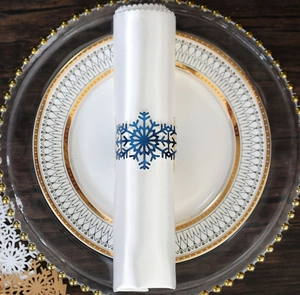 Detail of blue snowflake napkin ring on white satin fabric for Christmas table setting