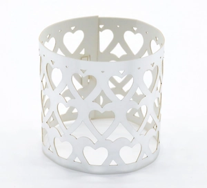 Close-up of white hollow heart patterns on a cylindrical decorative candle wrap holder
