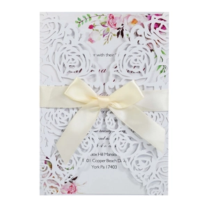 Detailed laser-cut white rose invitation with beige satin ribbon and floral inner card