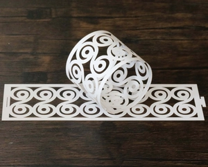 Close-up of white laser-cut paper napkin ring with elegant spiral pattern