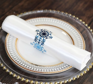 Close-up of a gradient blue snowflake napkin ring on white satin fabric napkin