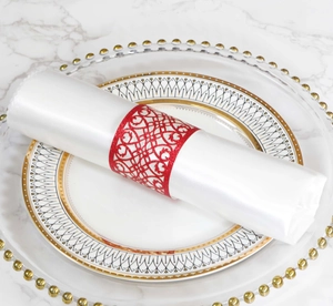Macro detail of red laser-cut napkin ring with intricate pattern on a white napkin