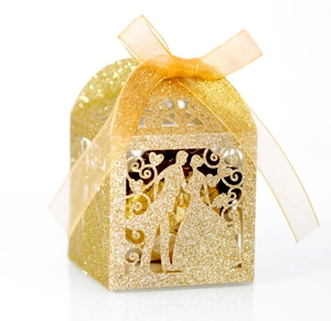 Detail of glittery laser-cut wedding favor box with bride and groom silhouette and ribbon