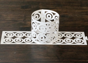 Close-up of laser-cut butterfly paper napkin ring with intricate white spiral patterns