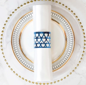Close-up of a blue heart-shaped cutout metal napkin ring on a white fabric napkin