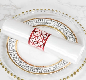 Detalle de servilletero rojo calado por láser con patrón geométrico sobre mesa elegante