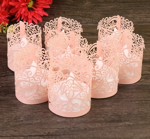 Close-up of laser-cut pink paper lanterns with floral leaf patterns on wooden background