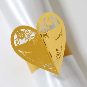 Détail macro du rond de serviette doré double cœur découpé au laser avec motif floral