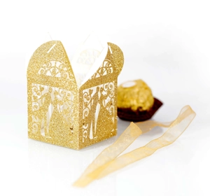 Detail of laser-cut gold glitter favor box with ribbon and bride and groom design