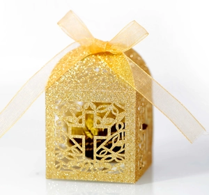 Close-up of golden glitter cross laser-cut favor box with delicate chiffon ribbon bow