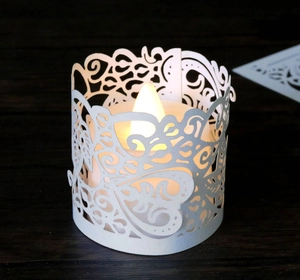 Detailed view of white hollowed paper lampshade with heart patterns and LED candle light