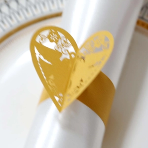 Détail macro du rond de serviette cœur doré découpé au laser avec motifs floraux ajourés