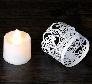 Close-up of a warm yellow LED candle light next to a white laser-cut maple leaf lampshade