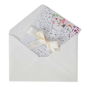 Close-up of laser-cut rose wedding invitation with silk ribbon and pearl paper finish