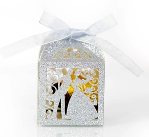 Close-up of laser-cut silver glitter wedding favor box with blue ribbon and bride silhouette