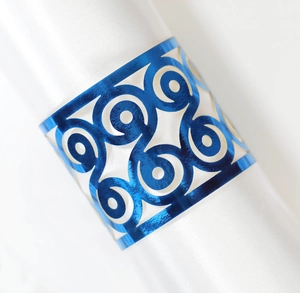 Detail of laser-cut blue metallic napkin ring with intricate spiral geometric patterns