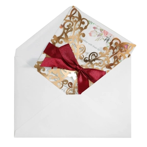 Laser cut rose gold wedding invitation with a red ribbon and floral insert with envelope