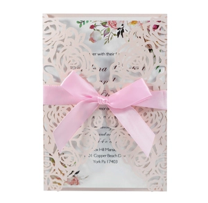 Close-up of laser-cut rose hollow invitation with elegant pink silk ribbon and inner card